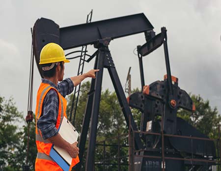 Workers standing and checking beside working oil pumps